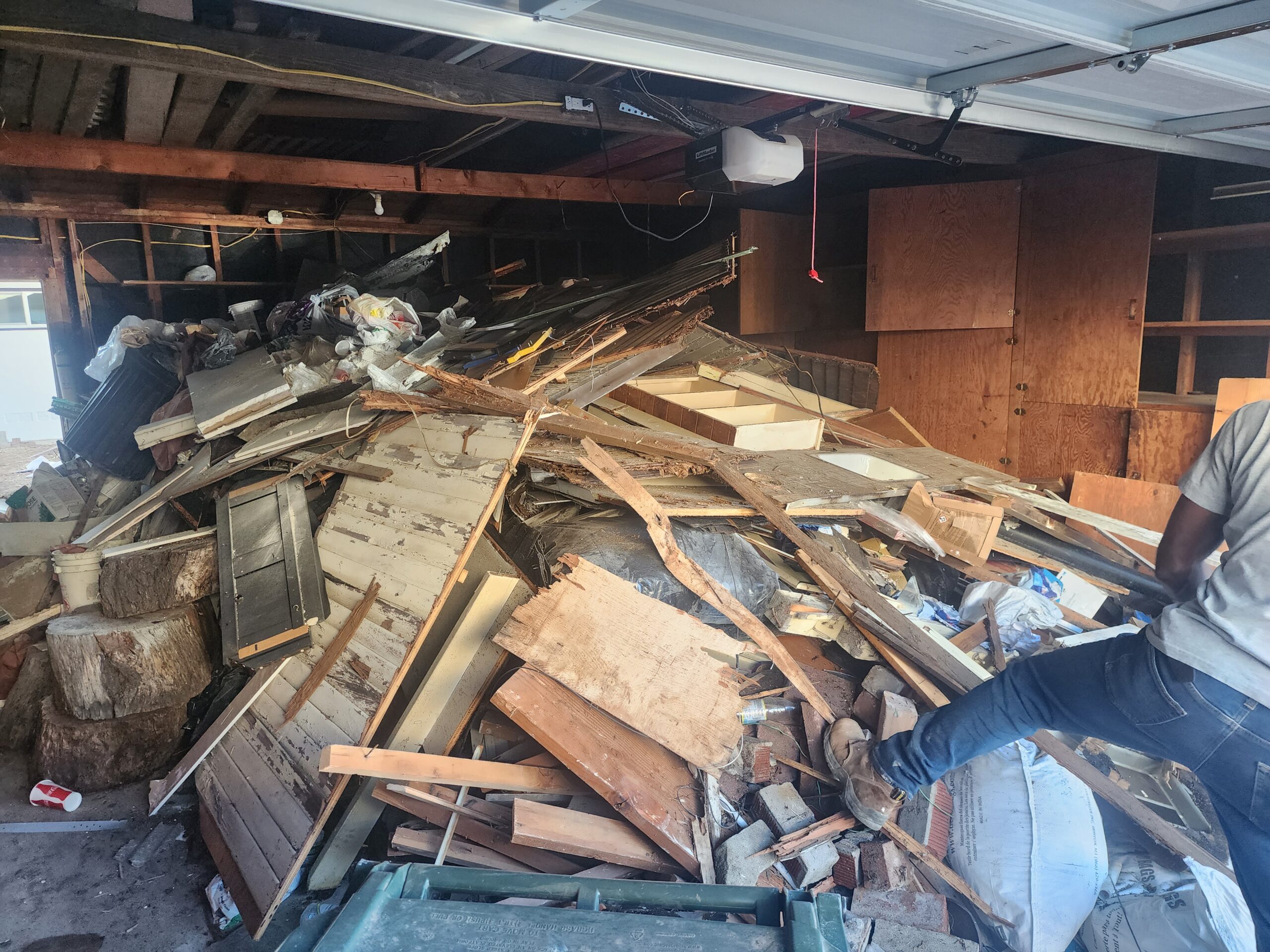 A man stands confidently in front of a large pile of assorted junk